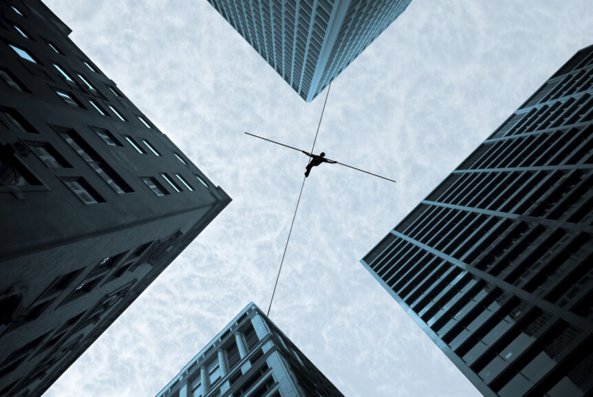 Balancing on a tight rope above city buildings